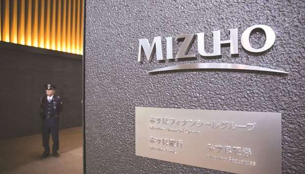 A security guard stands at the entrance to the Mizuho Financial Group headquarters in Tokyo. Mizuho Securities, the unit of Mizuho Financial Group, is interviewing analysts from competitors as it seeks to fill positions in mergers and acquisitions advisory and industry coverage.
