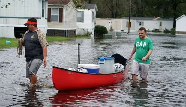 People walk through flooded street with a canoe after Hurricane Florence struck Piney Green, North Carolina