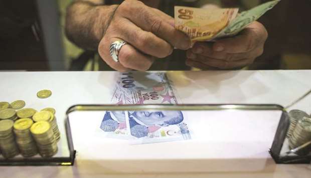 A cashier counts out Turkish lira banknotes on the counter of a foreign currency exchange store in Istanbul. Turkish lenders have been struggling to deal with a rising number of restructurings after the lira dropped about 40% against the dollar this year, hurting firmsu2019 ability to repay foreign-currency loans.