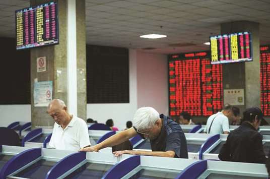 Investors look at computer screens showing stock information at a brokerage house in Shanghai. The Composite index closed up 1.8% to 2,699.95 points yesterday.