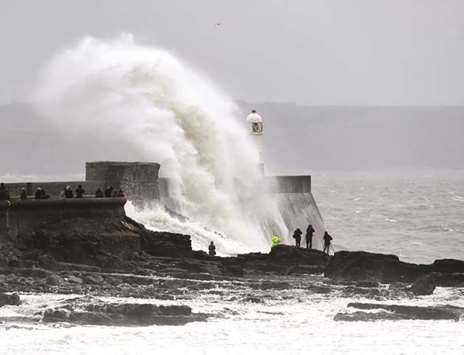 Waves crash over the lighthouse at Porthcawl, Wales, yesterday.