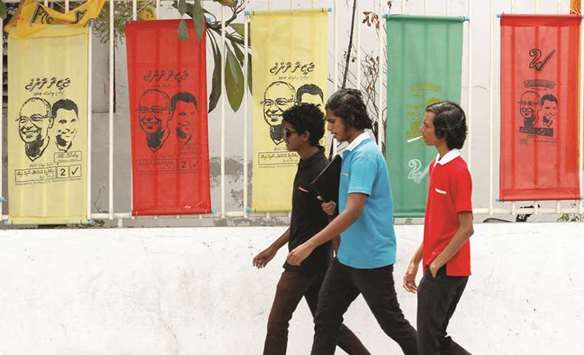 Youths walk past the posters of Ibrahim Mohamed Solih, Maldivian presidential candidate backed by the opposition coalition, on a road ahead of the presidential election in Male yesterday.