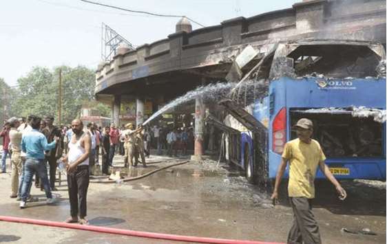 A firefighter sprays water on a bus of the Uttar Pradesh State Roadways Transport Corporation that was torched by a woman, in Varanasi yesterday.