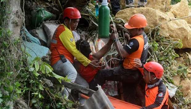Rescue workers provide first aid to a resident after a landslide triggered by rains hit a village in Naga City, Cebu province on Thursday.