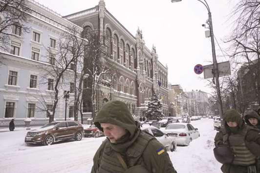 Ukrainian soldiers walk through snow past the headquarters of the Ukraine Central Bank in Kiev. u201cThere are talks on a new IMF programme that will allow Ukraine to pass the election year freely and maintain financial stability,u201d central bank deputy governor Oleh Churiy said yesterday.
