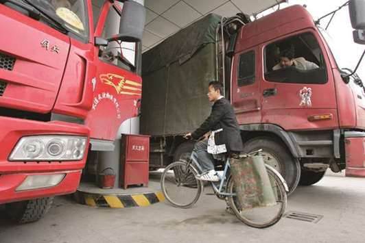 A man on bicycle waits for his turn to fill a container with diesel fuel at a gas station on the outskirts of Shanghai. Diesel accounts for about 30% of Chinau2019s appetite for petroleum products and is typically used to fuel trucks, as well as mining and construction equipment.