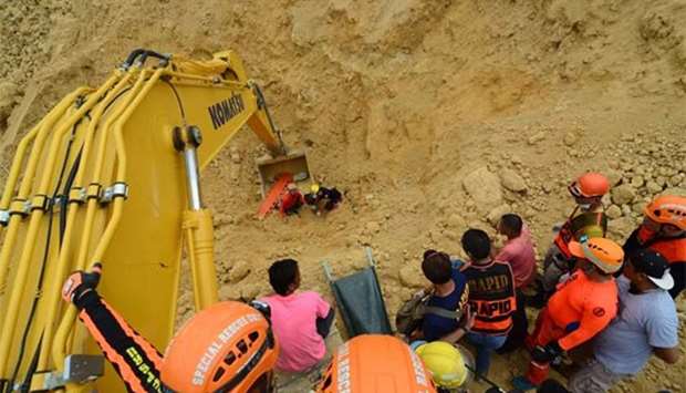 Rescue workers using a backhoe as they retrieve a body at the landslide site in Naga City on the popular tourist island of Cebu.