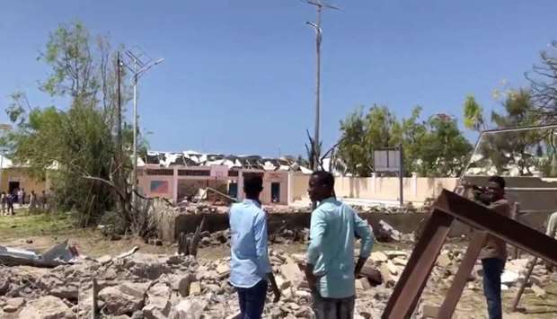 People look at debris at the site of a blast in Mogadishu, Somalia
