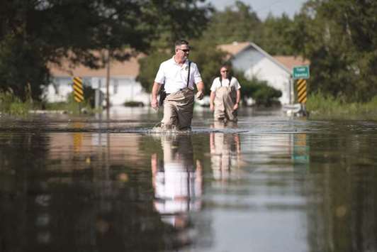 Government officials walk through flood waters near the Todd Swamp on Friday.