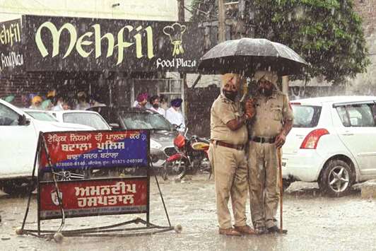 Two police officers stand under an umbrella as heavy rain falls in Amritsar, Punjab yesterday.