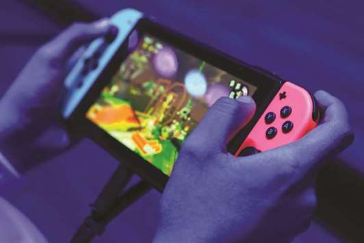 An attendee plays the Nintendo Switch video game console during E3 Electronic Entertainment Expo in Los Angeles. The company that created Super Mario and Zelda is finally embracing online gaming with the debut of its first online subscription service, charging $20 a year for users of its Switch console to play each other across the web.