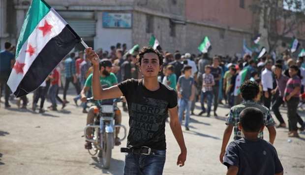 A Syrian youth waves an opposition flag during a demonstration against the Syrian government in the rebel-held town of Hazzanu, about 20 kilometres northwest of the city of Idlib