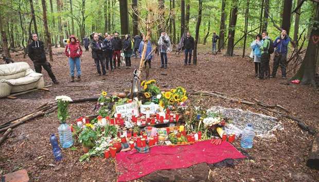 People gather yesterday around a makeshift memorial set up where a journalist died during the operations to evict protesters at the Hambach Forest.