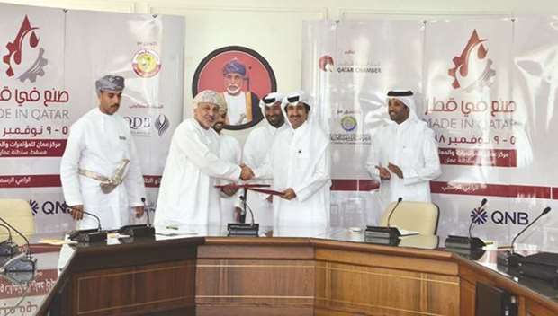 Saleh al-Sharqi and Salem al-Bahrani exchanging documents after signing the co-operation protocol to activate the Qatari-Omani business council.