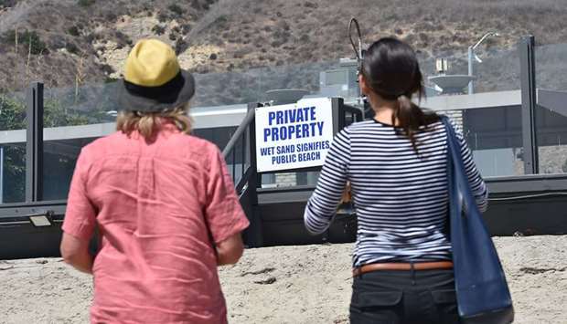 Linda Locklin (left) manager of Californiau2019s coastal access programme and Noaki Schwartz, spokesperson for the California Coastal Commission, examine a misleading sign posted on private beach front property in Malibu, California.
