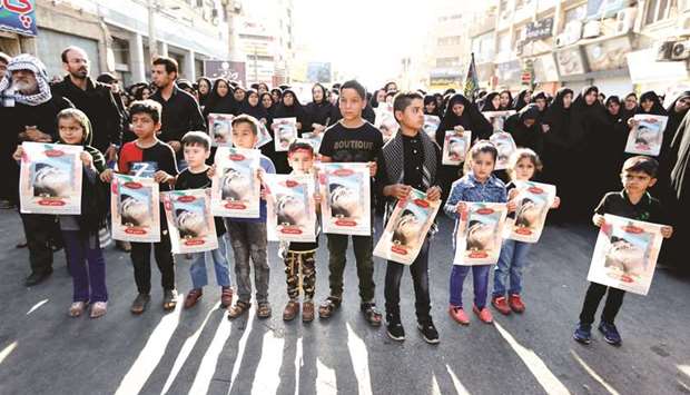 Iranian boys hold images of one of the victims Mohamed Taha Eghdami, 4, during a public funeral ceremony for those killed during an attack on a military parade on the weekend, in the southwestern city of Ahvaz, yesterday.