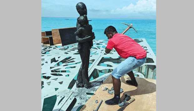 An axe-wielding policeman hacks down a statue in an underwater gallery in the Maldives.