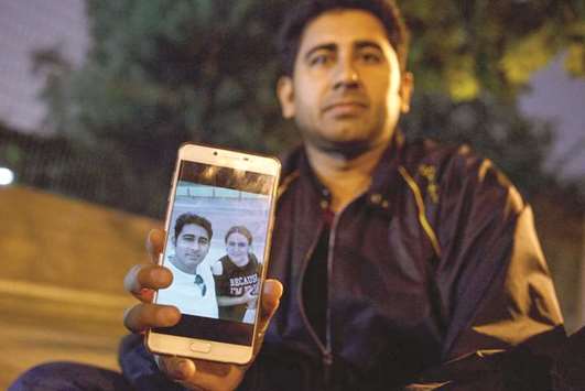 Mirza Imran Baig shows a picture of him and his wife Mailikemu Maimati as he sits outside the Pakistani embassy in Beijing.