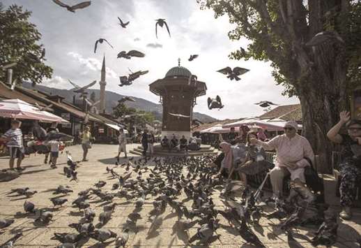 People feed pigeons next to an Ottoman-style fountain in Bascarsija Square, in Sarajevo, Bosnia. A favourable regulatory framework and political support, particularly advocated by Bakir Izetbegovic, current chairman of the presidency of Bosnia and Herzegovina, have accelerated the development of the Islamic finance sector in the country.