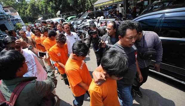 Indonesian policemen escort eights suspects of supporters of Bandung football following a violence beating to a Persija supporter one day earlier, in Bandung on September 24.