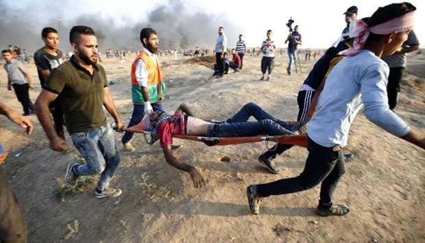 Demonstrators carry an injured Palestinian during clashes along the Israeli border fence, east of Gaza City.