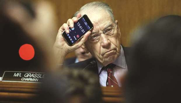 Republican Senator Chuck Grassley holds up the timer on his phone while Democratic Senator Cory Booker makes an impassioned speech during the Senate Judiciary Committee meeting.