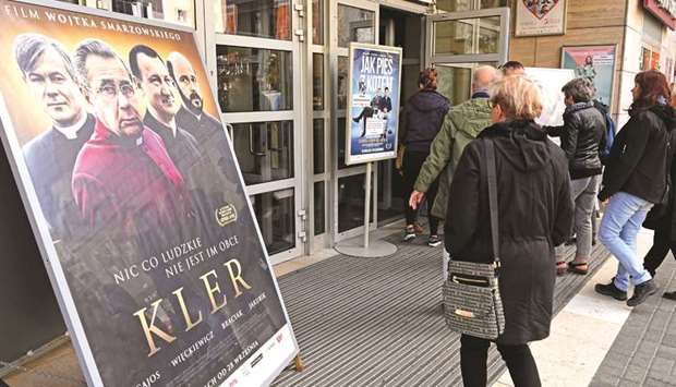 People pass by poster of movie Kler (The Clergy) at the entrance of a cinema in Warsaw.