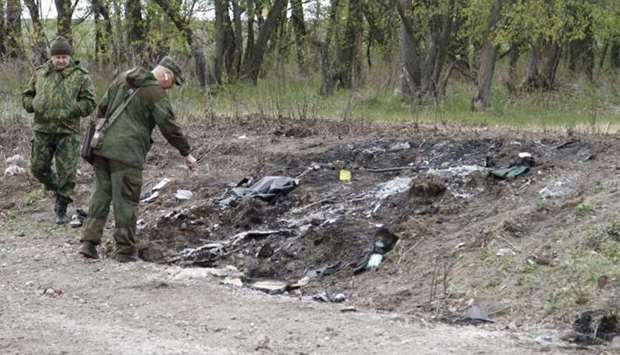 Servicemen inspect a site where a vehicle struck a landmine and exploded, near the village of Pryshyb outside Luhansk, Ukraine, on April 25, 2017