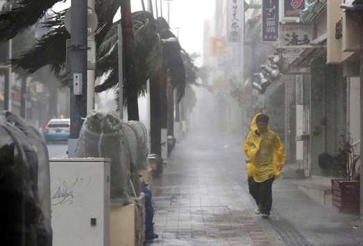 A passer-by walks in heavy rain and wind caused by Typhoon Trami in the prefectural capital Naha, on the southern island of Okinawa, in this photo taken by Kyodo yesterday.