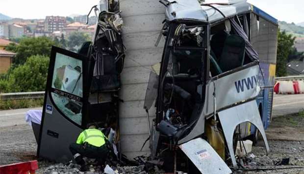 A civil guard surveys the wreckage of a bus crash in Aviles, Spain, on Monday.