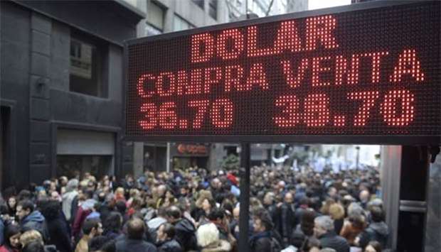 Demonstrators protesting against the economic policies of the government walk in front of a bureau de exchange in Buenos Aires on Monday.