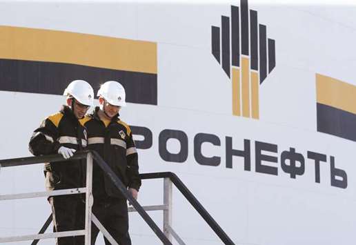 Workers stand next to a logo of Rosneft oil company at the central processing facility of the Rosneft-owned Priobskoye oil field outside the West Siberian city of  Nefteyugansk, Russia (file).  The combined revenue of Russiau2019s top five oil producers jumped 32% to more than 9.9tn roubles ($150bn), while total net income doubled to almost 1.25tn roubles.