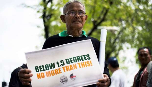 An environmental activist displays a placard during a demonstration in front of the United Nations building in Bangkok