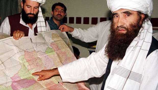 Jalaluddin Haqqani (R), the Taliban's Minister for Tribal Affairs, points to a map of Afghanistan during a visit to Islamabad, Pakistan, October 19, 2001, as his son Naziruddin (L) looks on