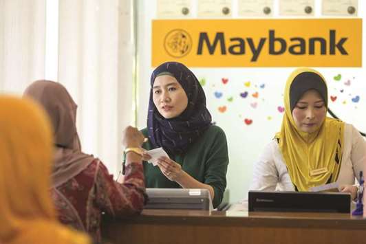 An employee serves a customer at the information counter inside a combined Malayan Banking (Maybank) and Maybank Islamic bank branch in Kuala Lumpur (file). The Switzerland-based IFSB on August 6 in Kuala Lumpur signed a memorandum of understanding to set up a joint working group which would develop and promote  technical standards for the implementation of effective and comprehensive Islamic deposit insurance systems.