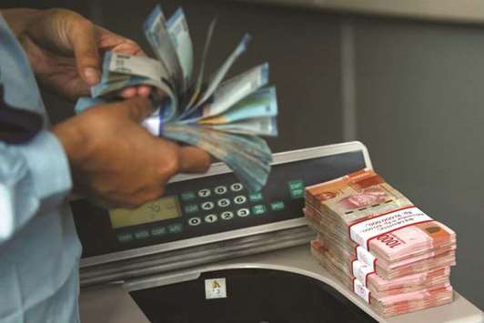 Indonesian rupiah banknotes are counted at a money changer in Jakarta. Yesterday, the rupiah touched 14,940 to the dollar, its weakest in 20 years.