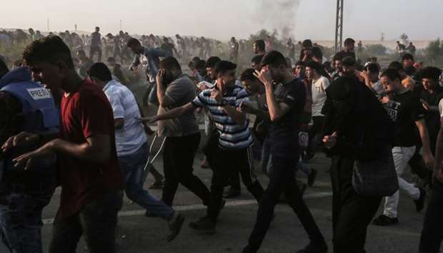 Palestinian protesters react to tear gas during clashes with Israeli forces near the Erez crossing with Israel yesterday