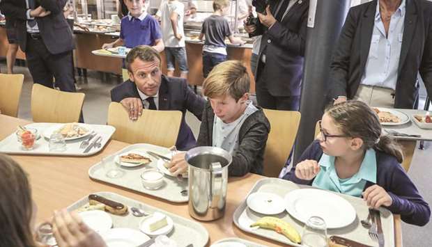 This picture taken on Monday shows Macron speaking with pupils in the canteen of a secondary school in Laval, France, at the start of the school year in France.