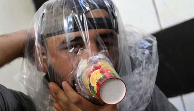 Hudhayfa al-Shahad tries an improvised gas mask in Idlib, Syria