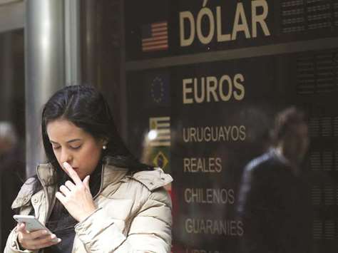 A woman looks at her cellphone as she stands in front of a currency exchange board in Buenos Airesu2019 financial district on Wednesday. South Americau2019s No 2 economy has a benchmark interest rate of 60% and inflation tops 31%.