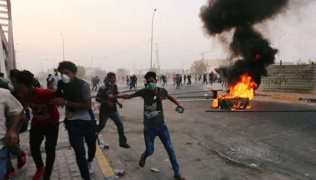 Iraqi protesters run during a protest near the building of the government office in Basra yesterday.