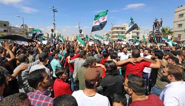 Syrian protesters wave the opposition flag as they demonstrate against the regime and Russia, in Idlib on Friday.