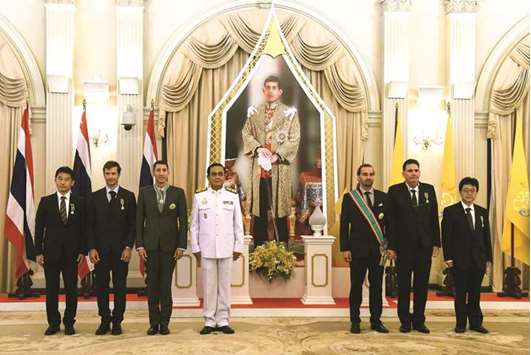 Japanese cave diver Shigeki Miyake, Belgian cave diver Ben Reymenants, American cave diver Joshua David Morris, Thai Prime Minister Prayut Chan-o-cha, Finnish cave diver Mikko Paasi, American cave diver Bruce Konefe and Japanese cave diver Hideki Furihata pose in front of a depiction of Thai King Maha Vajiralongkorn at the Royal Decoration Ceremony for aiding the rescue of the Wild Boars football team from Tham Luang cave, at the Royal Thai Government House in Bangkok yesterday.