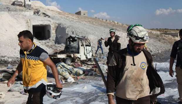 Syrian civil defence members search near a burned vehicle and personal belongings at a site in Hass town after an airstrike by pro-regime forces on the south of Idlib province.