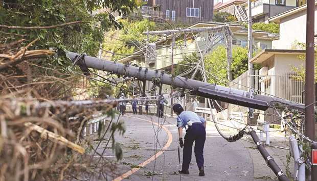 A police officer inspects damage caused by Typhoon Faxai in Kamakura, Kanagawa prefecture, yesterday.