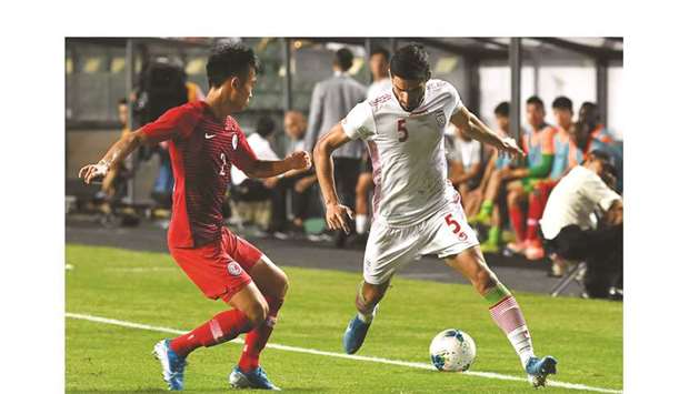 Iranu2019s Milad Mohammadi (R) fights for the ball with Hong Kongu2019s Tsui Wang Kit during the second round Group C qualification match at the Hong Kong Stadium in Hong Kong yesterday.