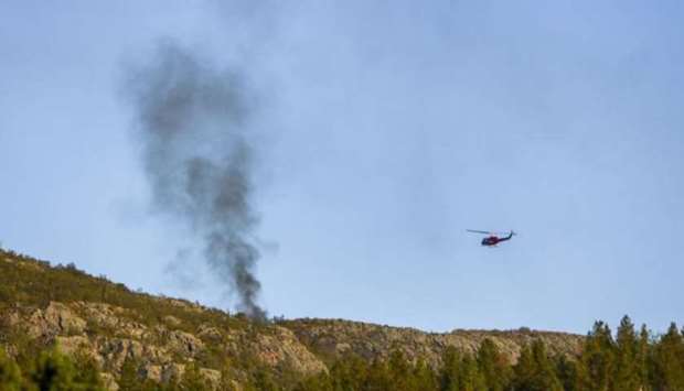 The helicopter of  an emergency service team hovers over the site where an Airbus AS350 helicopter operated by Helitrans crashed Sunday. Photo courtesy: ALTAPOSTEN