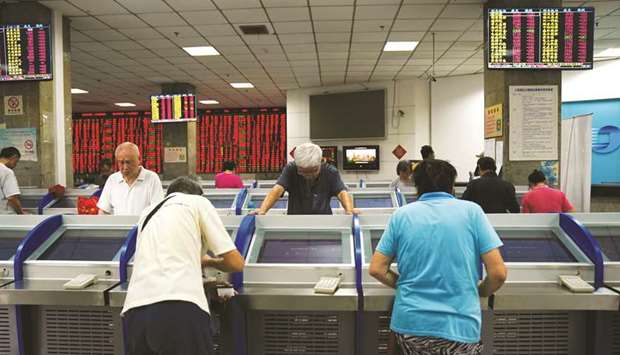 Investors look at computer screens showing stock information at a brokerage house in Shanghai. The bourse added 0.8% to 3,031.24 points yesterday.