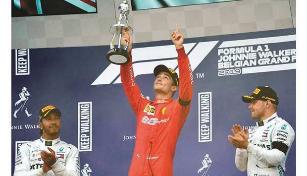 Ferrari driver Charles Leclerc (centre) holds the winneru2019s trophy and gestures towards the sky in tribute to late French driver Anthoine Hubert as second-placed Mercedes driver Lewis Hamilton (left) and third-placed Mercedes driver Valtteri Bottas applaud on the podium for the Belgian Grand Prix at Spa-Francorchamps yesterday. (AFP)