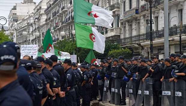 Algerian protesters wave their national flags next to security forces during a demonstration against the ruling class in the capital Algiers . AFP
